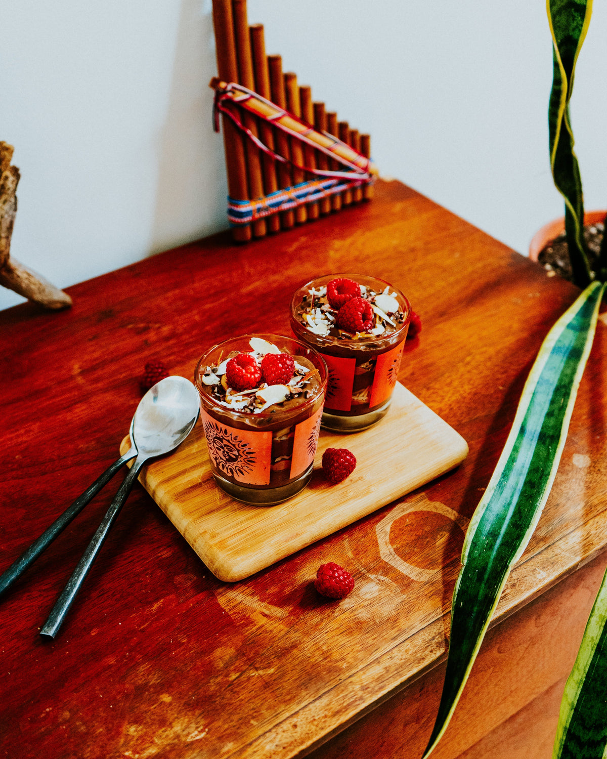 Cacao avocado mousse in small glass jars topped with raspberries