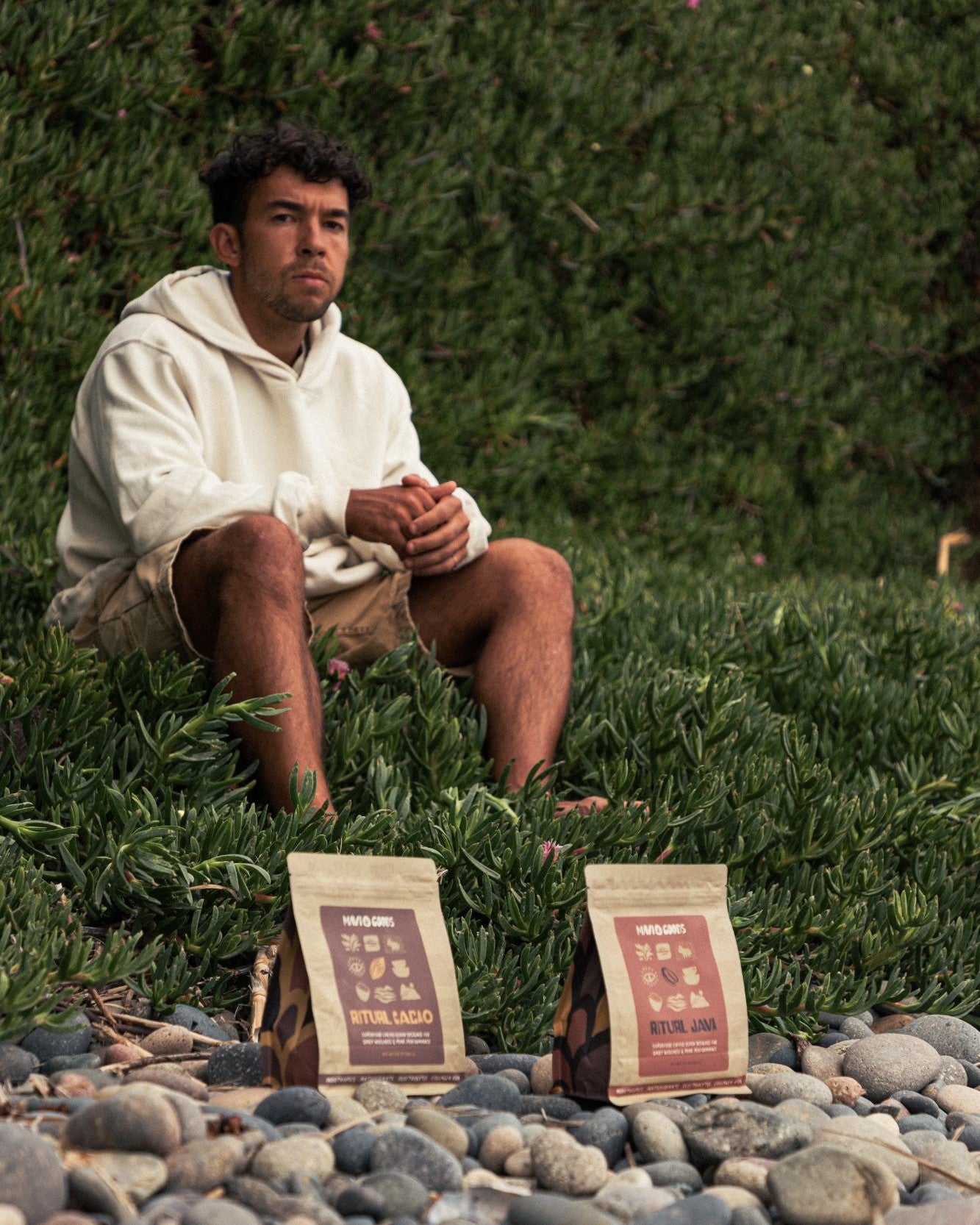 Mavi Goods founder Jason Pabst sitting on ice plant behind bags of Ritual Cacao and Ritual Java