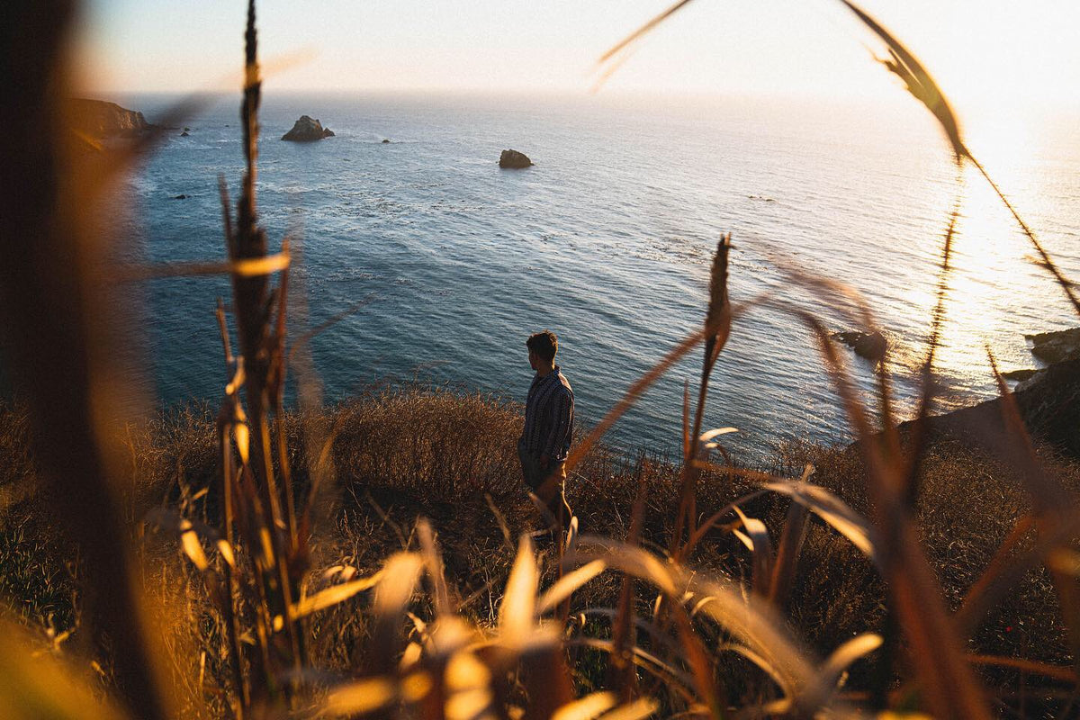 Mavi Goods founder Jason Pabst on a coastal cliff at golden hour, looking out over the ocean