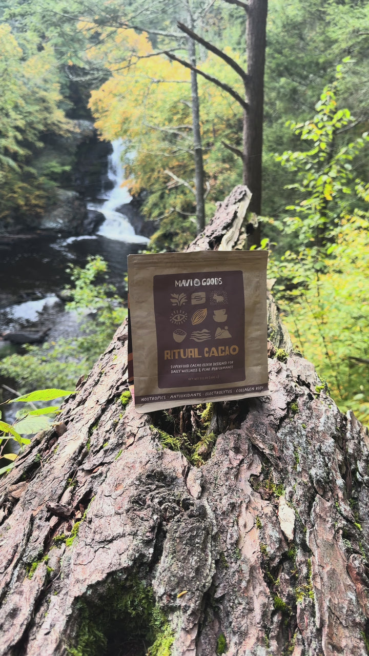 Ritual Cacao bag on a tree stump beside a forest waterfall